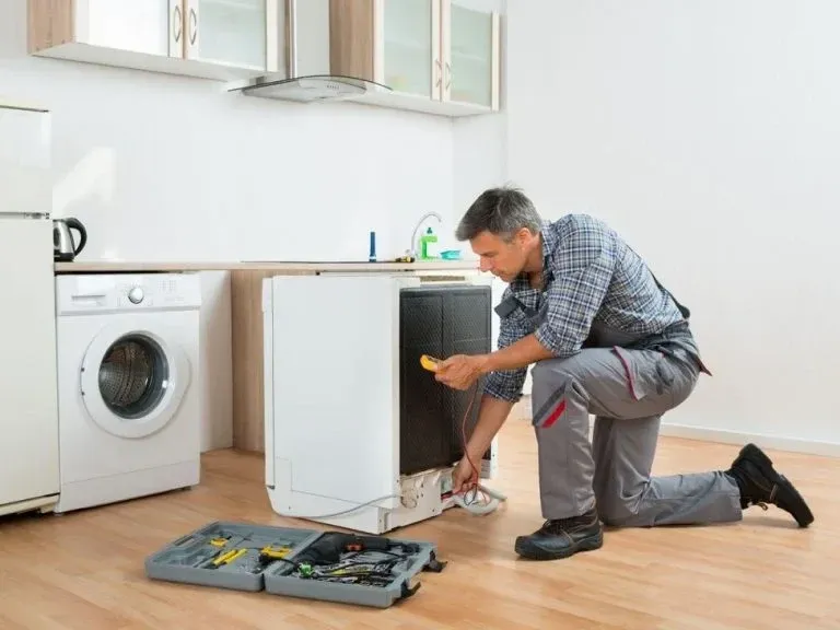 Technician testing a pulled-out dishwasher with a multimeter