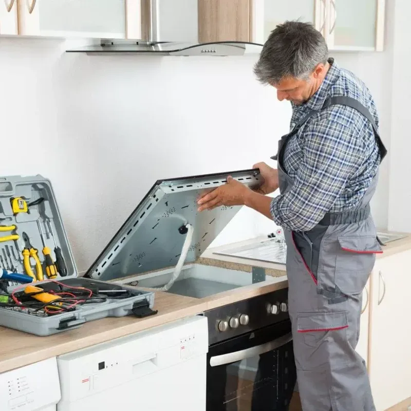 Technician lifting out a cooktop to reach its wiring, toolbox beside it