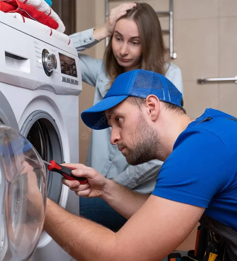 Technician repairing a front-load dryer as the homeowner watches
