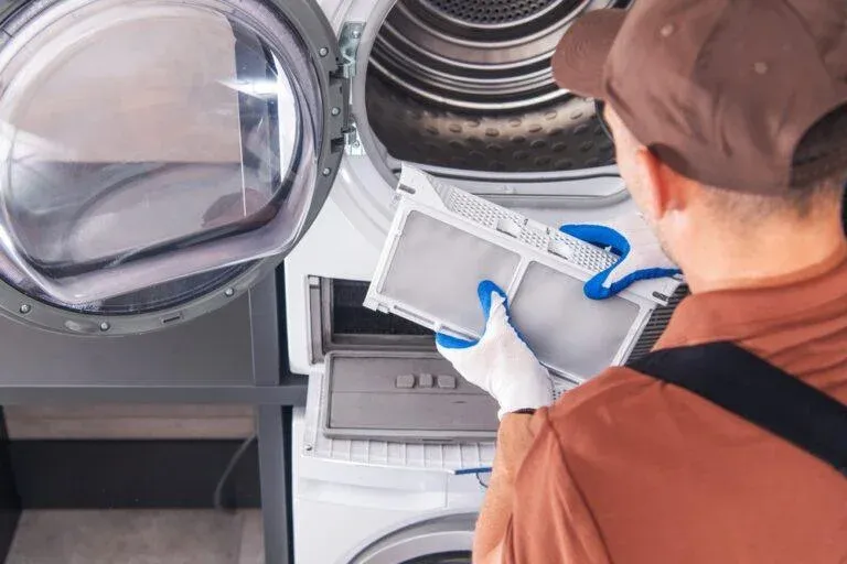 Technician cleaning a dryer lint filter during a repair in Groveland, FL