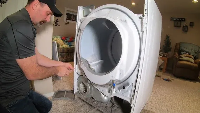 Technician repairing a dryer with its front panel removed