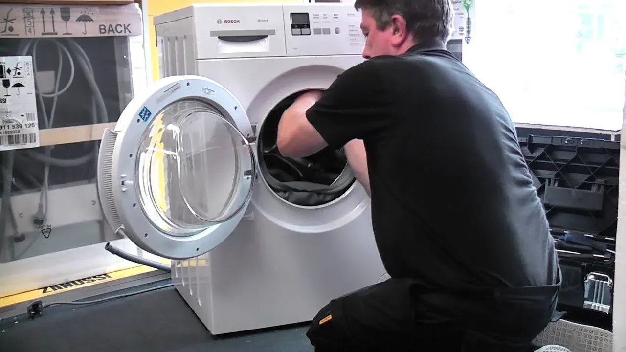 Technician repairing the drum of a front-load washer on an emergency call