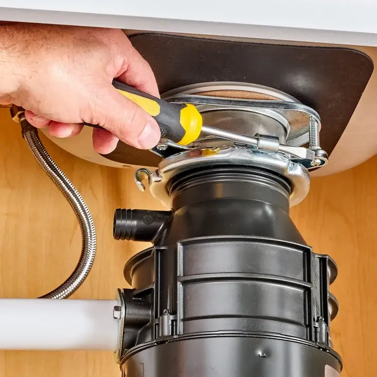 Ramson Appliances technician repairing a garbage disposal under a kitchen sink in Groveland, FL
