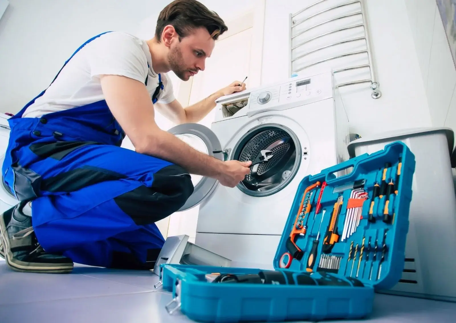 Technician repairing a front-load washer with an open toolkit in Groveland, FL