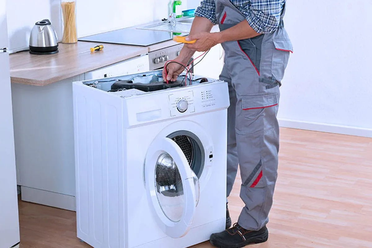 Technician testing the wiring of a front-load washer in a Groveland kitchen